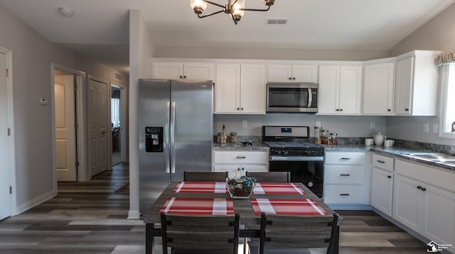 kitchen featuring white cabinets, dark hardwood / wood-style flooring, stainless steel appliances, and an inviting chandelier