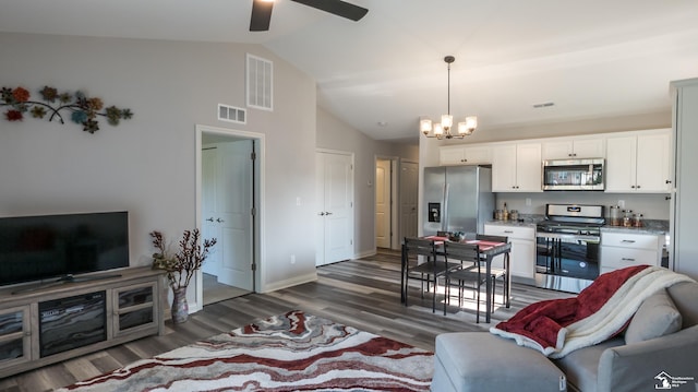 living room featuring ceiling fan with notable chandelier, high vaulted ceiling, and dark wood-type flooring