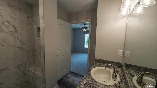 bathroom with ceiling fan, a tile shower, wood-type flooring, and vanity