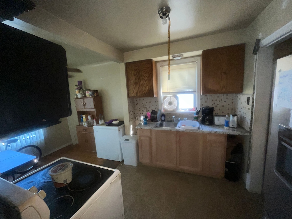 8275 Minock St, Detroit, MI 48228 - kitchen with white electric stove, a sink, backsplash, and light countertops