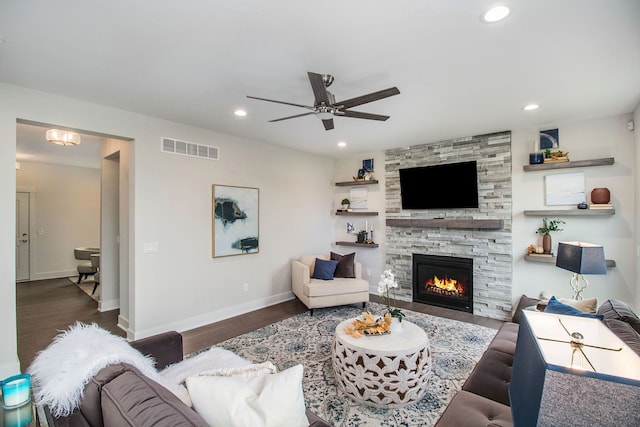 living room featuring a stone fireplace, ceiling fan, and dark hardwood / wood-style floors