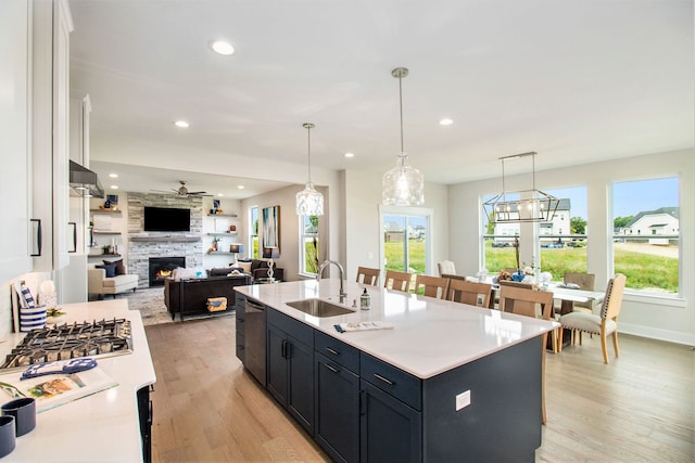 kitchen featuring white cabinets, a center island with sink, light wood-type flooring, and sink