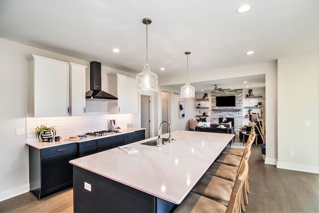 13327 Demil Dr, Romeo, MI 48065 - kitchen with wall chimney range hood, a sink, light wood-style flooring, decorative backsplash, and a large island with sink