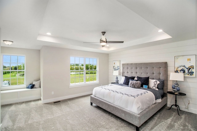 bedroom featuring ceiling fan, a raised ceiling, and multiple windows