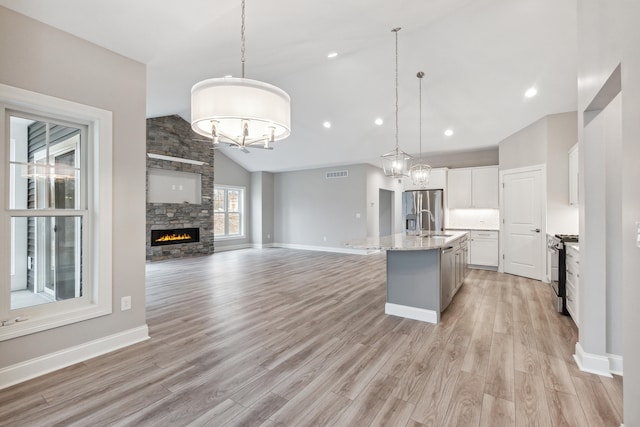 kitchen with pendant lighting, stainless steel appliances, white cabinetry, and an island with sink