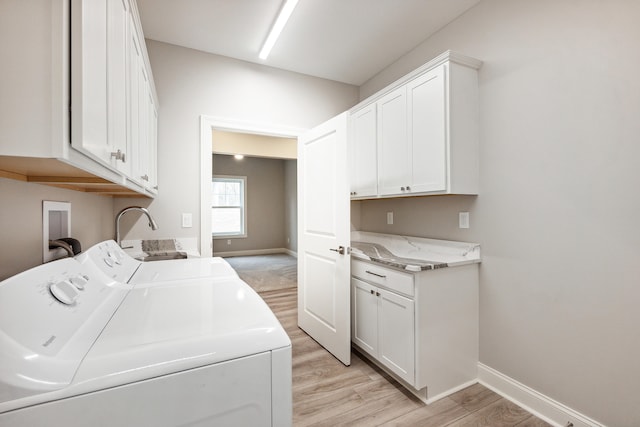 laundry room featuring cabinets, independent washer and dryer, and light wood-type flooring