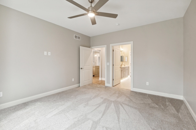 unfurnished bedroom featuring ensuite bathroom, ceiling fan, and light colored carpet