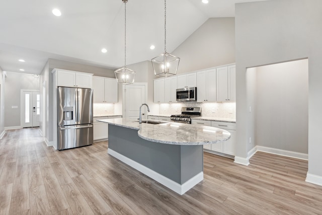 kitchen with appliances with stainless steel finishes, light wood-type flooring, sink, high vaulted ceiling, and white cabinets