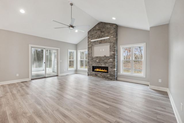 unfurnished living room featuring ceiling fan, a stone fireplace, light wood-type flooring, and high vaulted ceiling