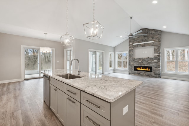 kitchen with plenty of natural light, a stone fireplace, sink, and a kitchen island with sink