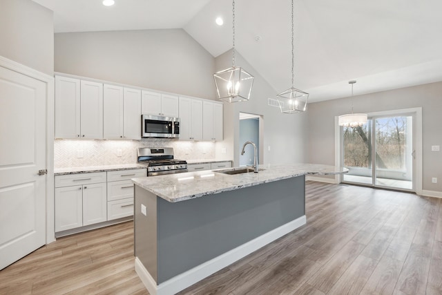 1140 Lochaven Cir Unit 10B, Hillsdale, MI 49242 - kitchen featuring appliances with stainless steel finishes, a sink, high vaulted ceiling, a kitchen island with sink, and white cabinets