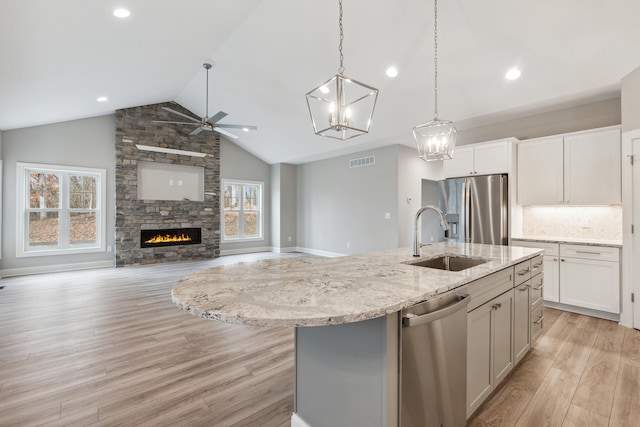 kitchen featuring a center island with sink, sink, a fireplace, appliances with stainless steel finishes, and light hardwood / wood-style floors