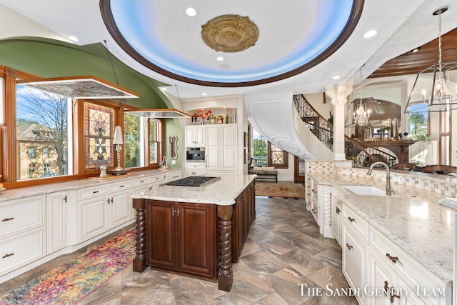 kitchen with plenty of natural light, a kitchen island, a raised ceiling, and sink