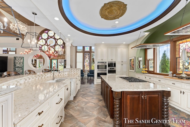 kitchen featuring a breakfast bar, gas stovetop, a raised ceiling, sink, and a large island