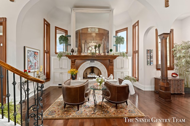 living area featuring a premium fireplace, a towering ceiling, and dark hardwood / wood-style floors