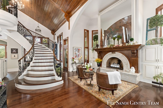 living area featuring high vaulted ceiling, wood ceiling, dark wood-type flooring, and a premium fireplace