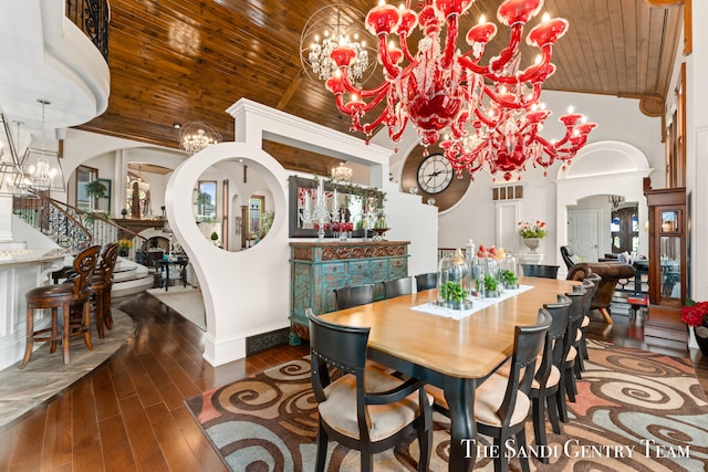 dining space featuring dark hardwood / wood-style flooring, wooden ceiling, a towering ceiling, and a chandelier