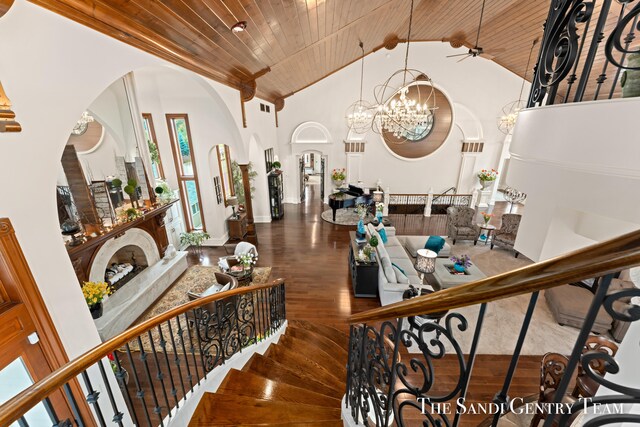 staircase with wooden ceiling, a high end fireplace, high vaulted ceiling, hardwood / wood-style floors, and ceiling fan with notable chandelier