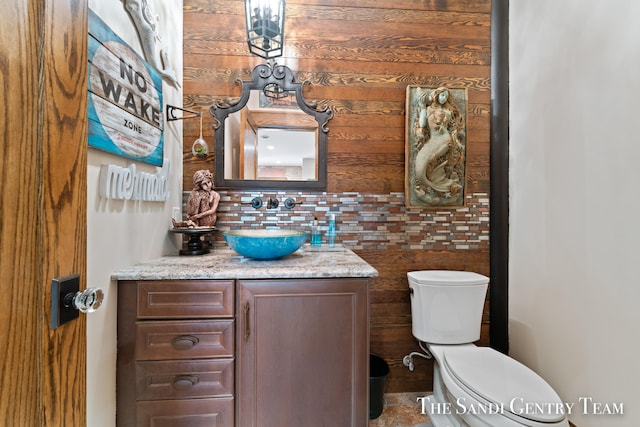 bathroom featuring vanity, toilet, and wooden walls