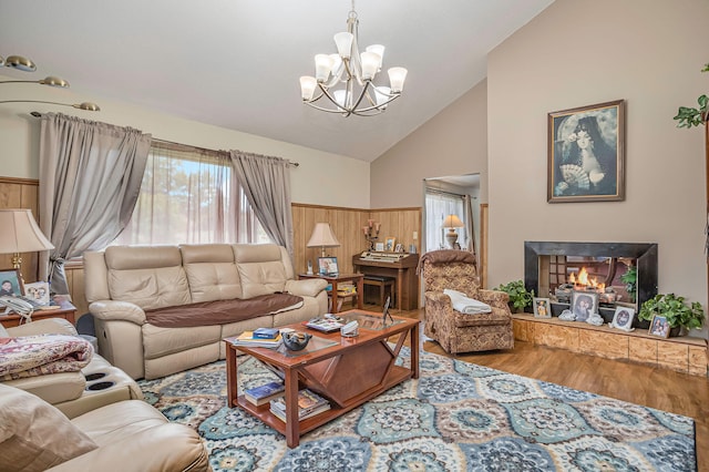 living room with wooden walls, hardwood / wood-style floors, high vaulted ceiling, and a notable chandelier