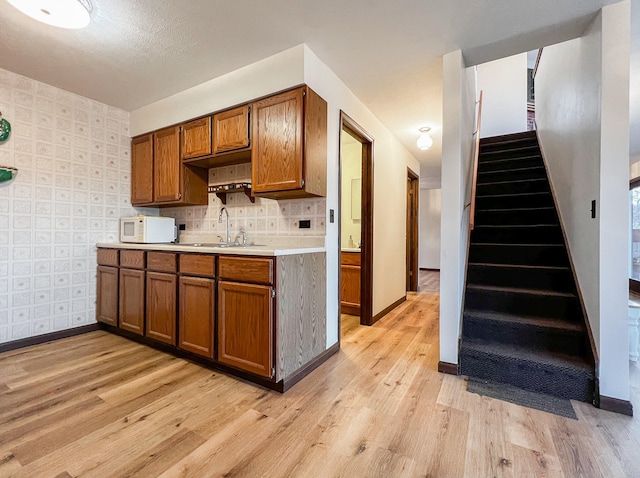 kitchen with backsplash, light hardwood / wood-style floors, and sink