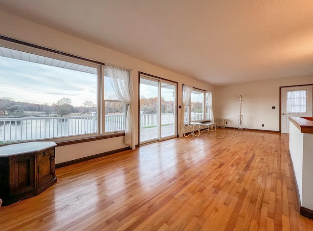 unfurnished living room featuring a water view and light hardwood / wood-style flooring