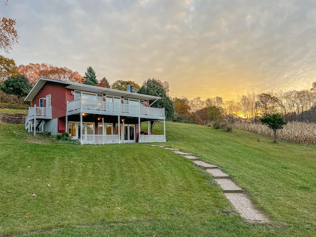 back house at dusk with a wooden deck and a yard