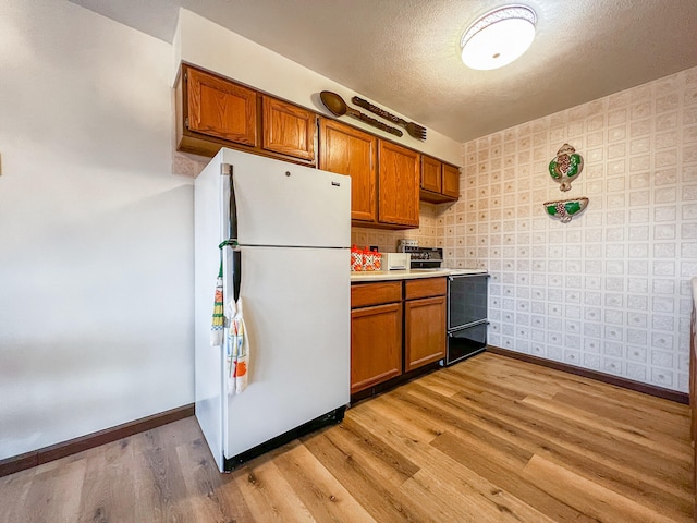 kitchen with a textured ceiling, light hardwood / wood-style floors, electric range oven, and white refrigerator