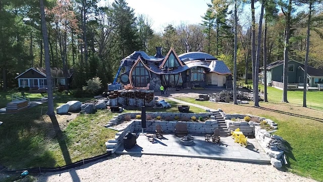 9554 Fowler Ln, Rapid City, MI 49676 - back of house with a fire pit, a patio, and a lawn