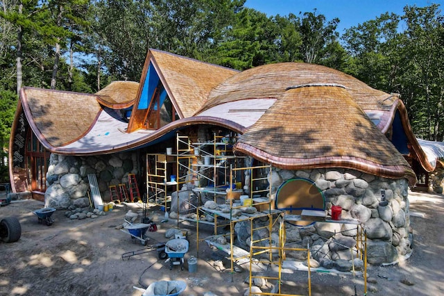 9554 Fowler Ln, Rapid City, MI 49676 - view of property exterior with stone siding, roof with shingles, and view of wooded area
