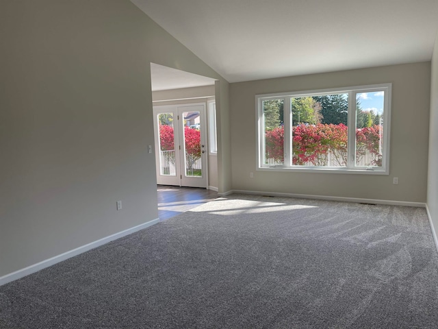 unfurnished room featuring french doors, dark carpet, and vaulted ceiling