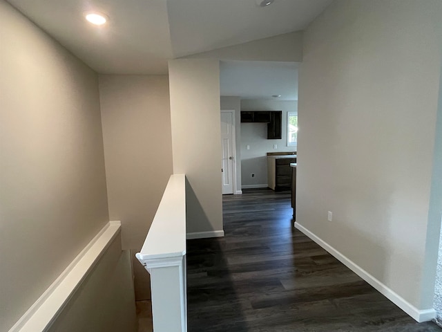 hallway with dark wood-type flooring and vaulted ceiling