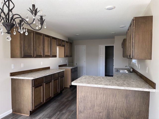 kitchen with a notable chandelier, dark hardwood / wood-style floors, dark brown cabinetry, and sink