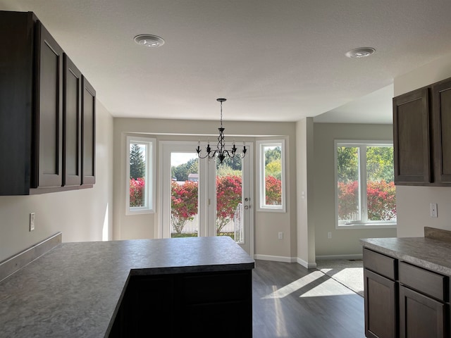 kitchen with a notable chandelier, dark brown cabinets, wood-type flooring, and decorative light fixtures