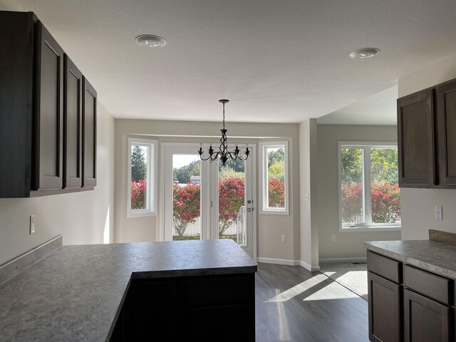 260 Windemere Pl, West Branch, MI 48661 - kitchen with dark wood-style flooring, a peninsula, a chandelier, baseboards, and decorative light fixtures