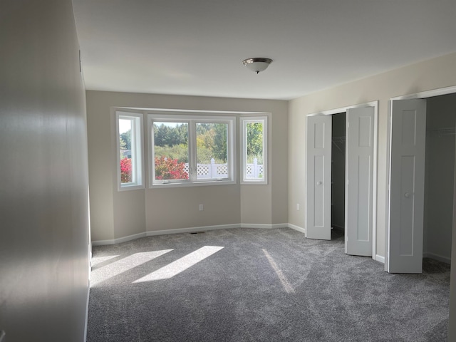 unfurnished bedroom with carpet floors and multiple closets