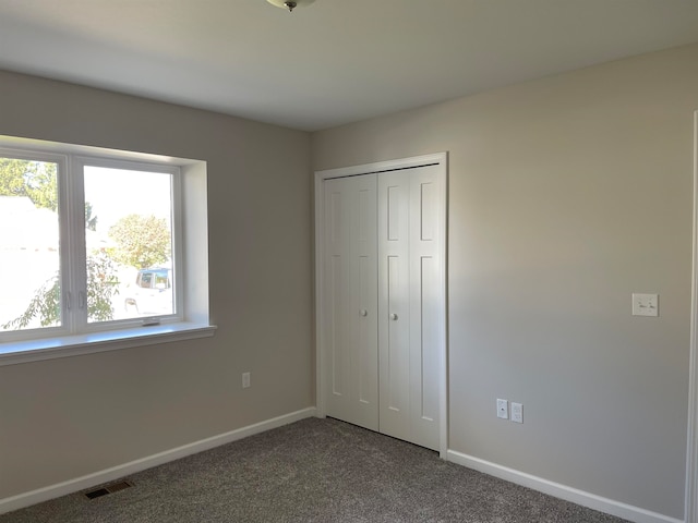 unfurnished bedroom featuring dark carpet and a closet