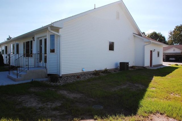 view of side of home featuring a lawn and central air condition unit