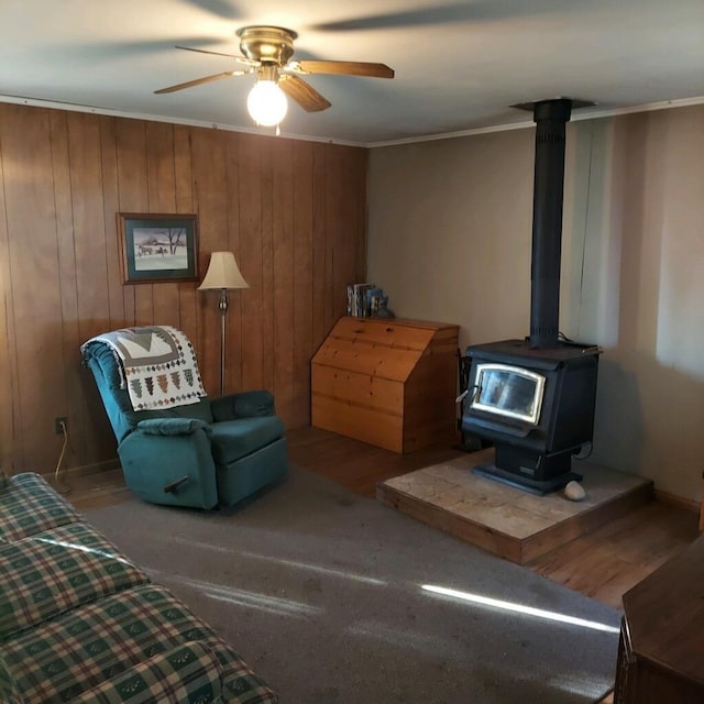 1400 Rainbow Park Trl, Luzerne, MI 48647 - sitting room with ceiling fan, a wood stove, ornamental molding, wooden walls, and wood finished floors