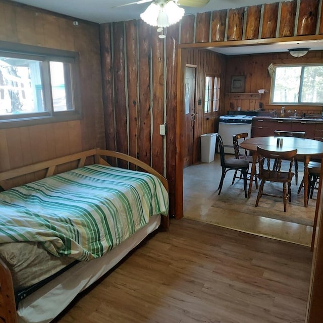 1400 Rainbow Park Trl, Luzerne, MI 48647 - bedroom with wooden walls, multiple windows, wood finished floors, and a sink