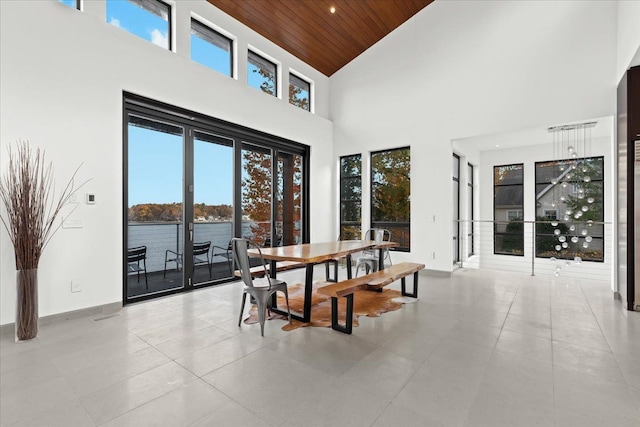 tiled dining room with a healthy amount of sunlight, a water view, high vaulted ceiling, and wooden ceiling