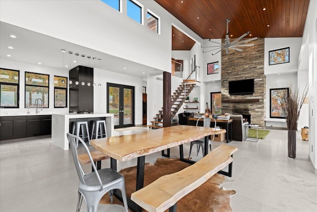 dining room featuring a fireplace, high vaulted ceiling, ceiling fan, and wood ceiling