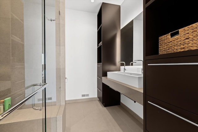 bathroom with tile patterned floors, a shower with shower door, and sink