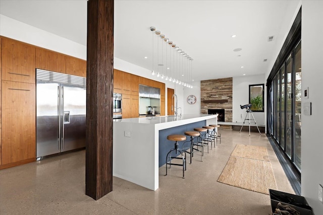 kitchen with wooden walls, a center island with sink, plenty of natural light, and appliances with stainless steel finishes