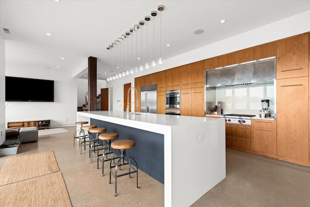 kitchen featuring a large island, sink, hanging light fixtures, stainless steel appliances, and a breakfast bar area