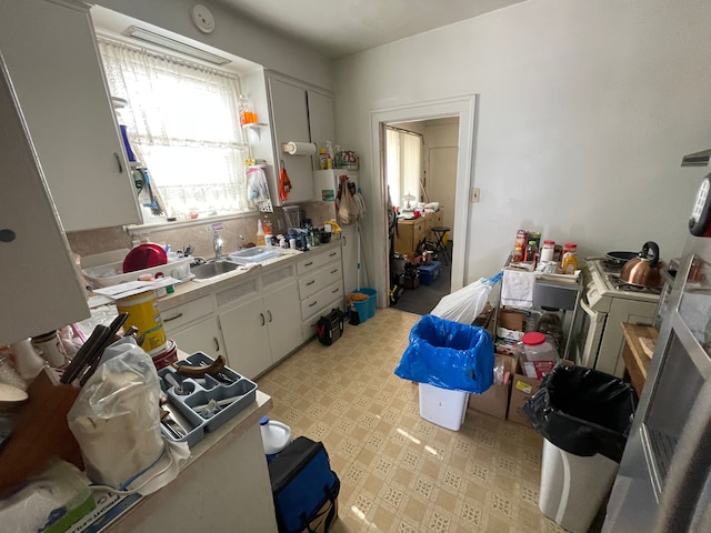 kitchen with washer / clothes dryer, white cabinetry, and sink