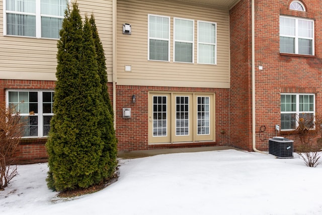 176 Sea Breeze Dr Unit 6, Detroit, MI 48214 - snow covered back of property featuring cooling unit, brick siding, and a patio