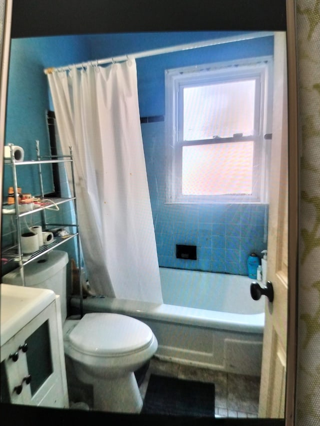 bathroom with shower / tub combo with curtain, tile patterned flooring, and toilet