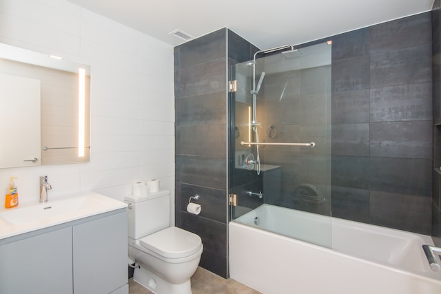 full bathroom featuring tasteful backsplash, toilet, shower / bath combination with glass door, vanity, and tile walls