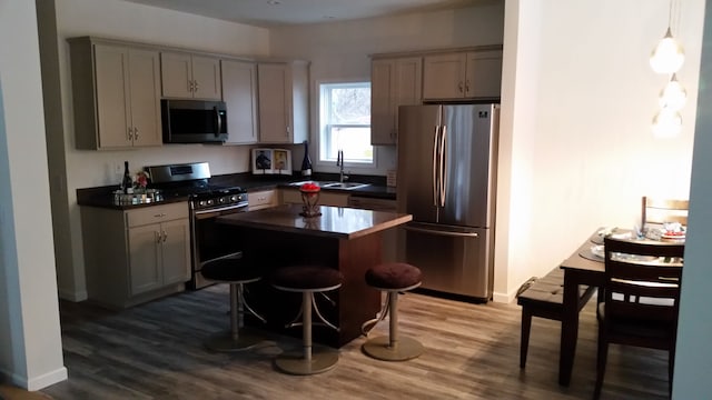 kitchen with gray cabinetry, a breakfast bar, stainless steel appliances, and hardwood / wood-style flooring